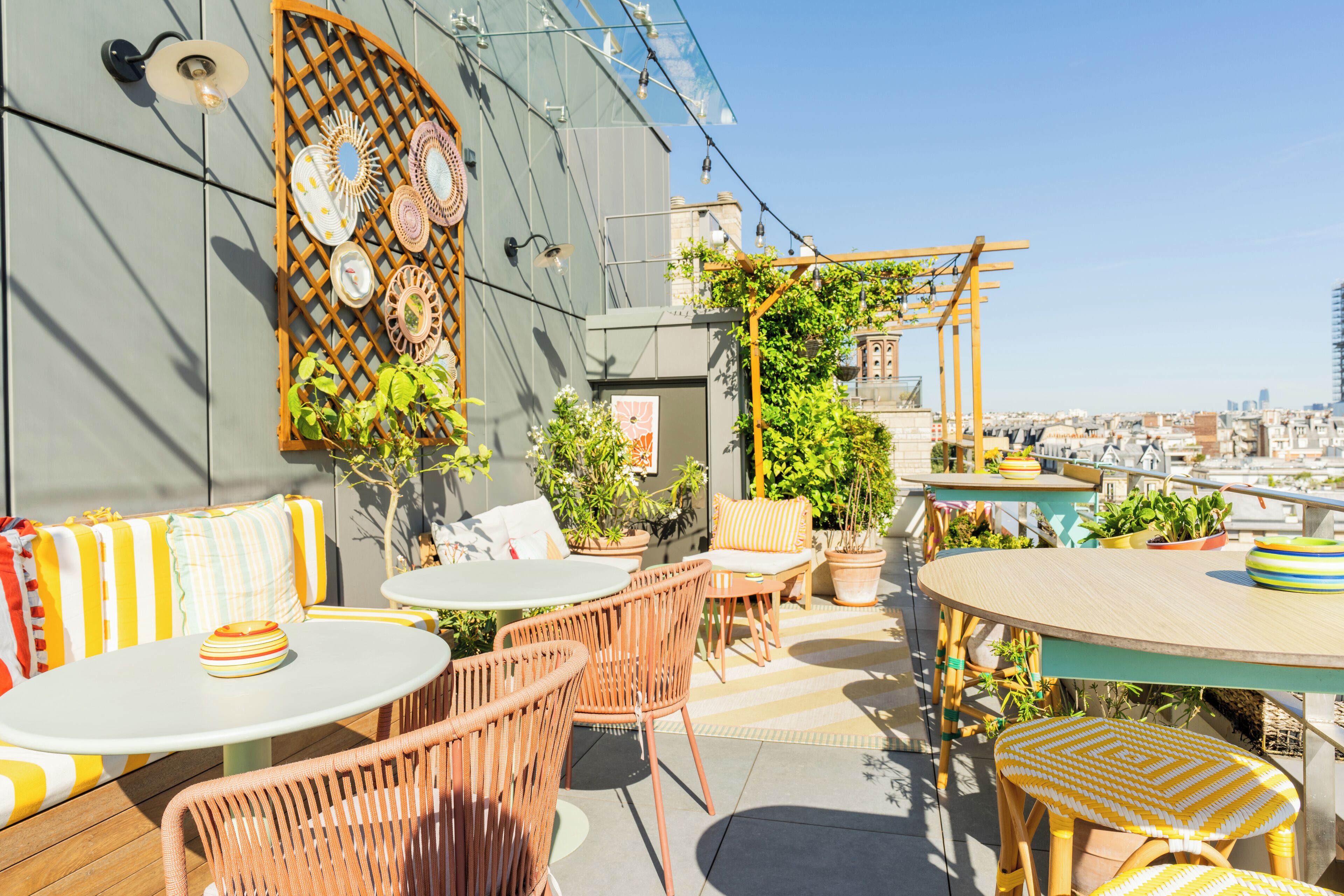Un patio al aire libre con mobiliario de mimbre, plantas en macetas y una pared decorativa.