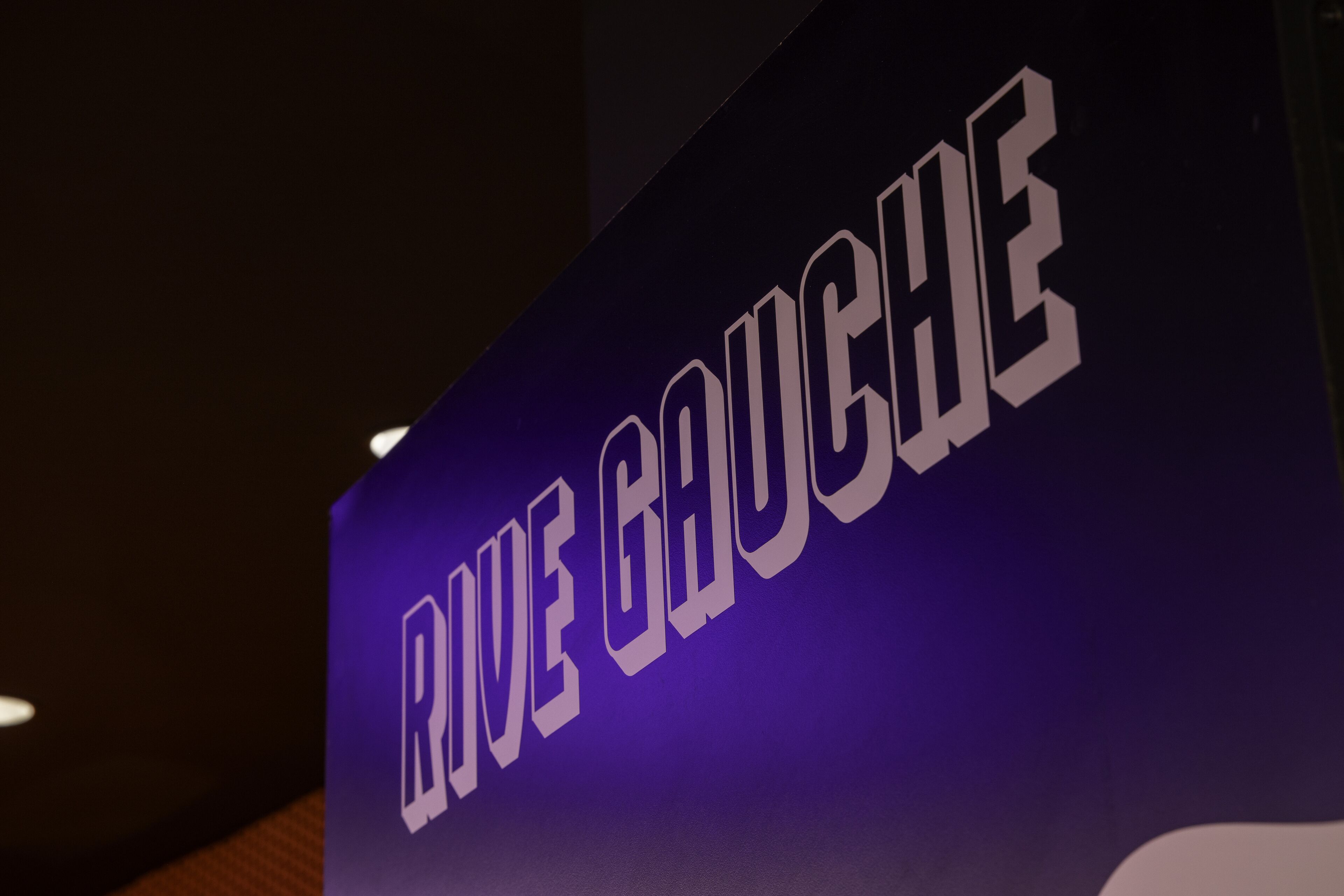 A sign with the text "RUE GACHE" on a purple background.