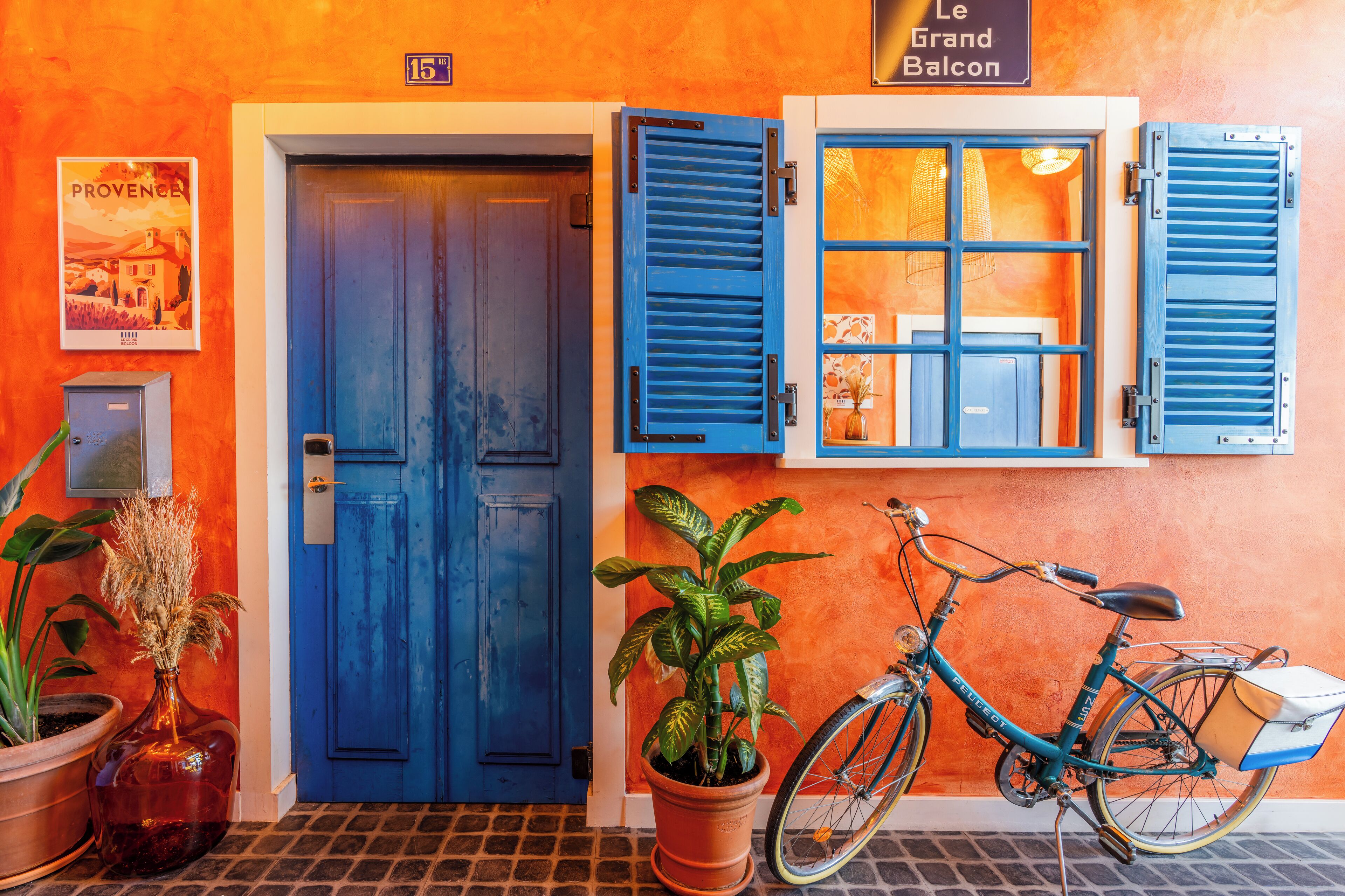 A blue door with a number 15 sign above it, a potted plant, and a bicycle with a basket.