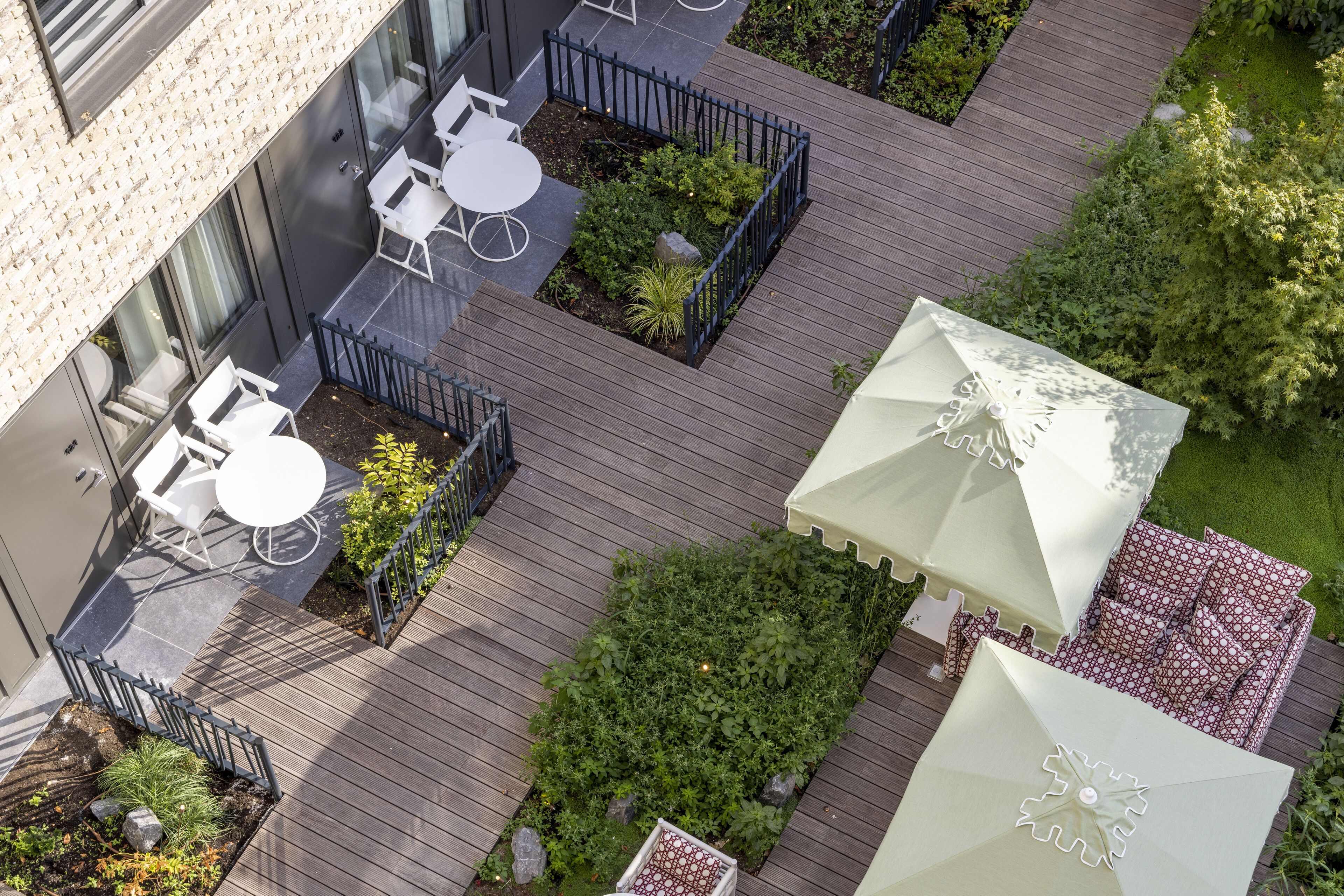 An aerial view of a rooftop garden with outdoor seating, a small pool, and umbrellas.