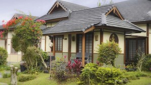 Ein traditionelles japanisches Haus mit einem Ziegeldach, Holzbalken und einem kleinen Garten mit verschiedenen Pflanzen und Blumen.
