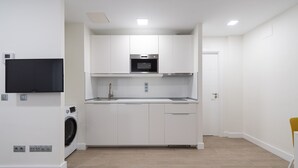 A modern kitchen with white cabinets, a built-in oven, and a washing machine.