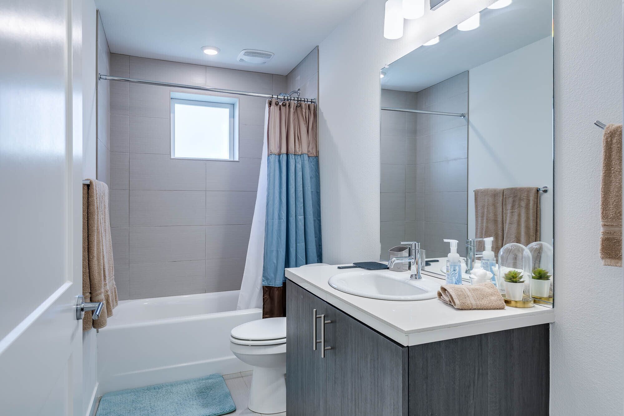 A modern bathroom with a bathtub, toilet, and vanity with a mirror.
