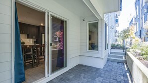 A residential building with a sliding glass door leading to a dining area with a table and chairs.