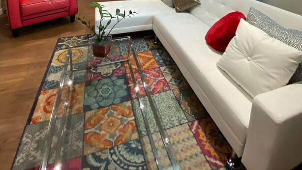 A living room with a white sofa, a red chair, a colorful rug, and a ceiling light.