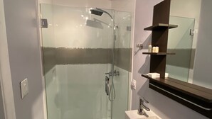 A modern bathroom with a glass-enclosed shower, a white sink, and a mirror with a dark frame.