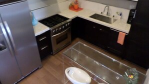 A compact kitchen with a stainless steel refrigerator, a gas stove, a built-in oven, a sink, and a small countertop area.