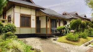 A traditional Japanese-style building with a tiled roof, a stone pathway leading to the entrance, and well-maintained greenery. - VILLA ADE - 0224 KOTA BUNGA PUNCAK (Cipanas)