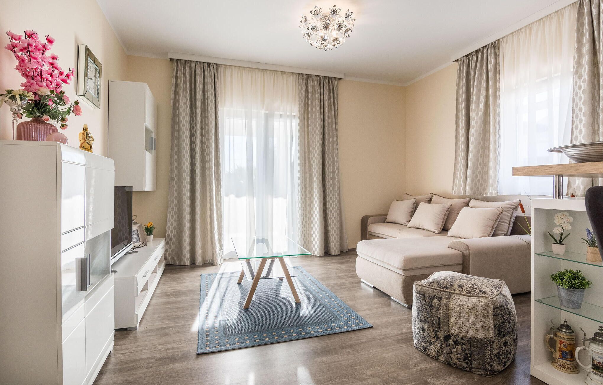 A modern living room with a sofa, ottoman, and a glass coffee table.