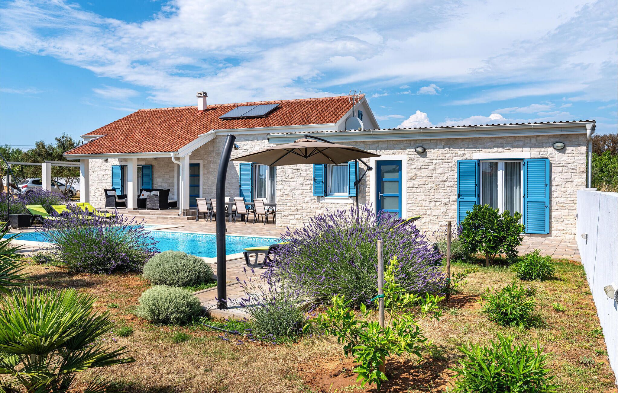A two-story house with a swimming pool, outdoor seating, and a garden with various plants.