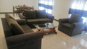 A living room with a sectional sofa, a coffee table, and a dining area in the background. - Signature Kandy (Kandy)