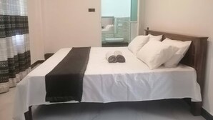 A hotel room with a bed, a bathroom visible through an open door, and a balcony with a glass railing. - Signature Kandy (Kandy)
