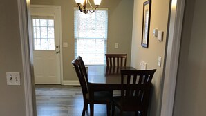 A dining area with a wooden table and chairs, a chandelier, and a window with blinds. - House near Lee University (Cleveland)