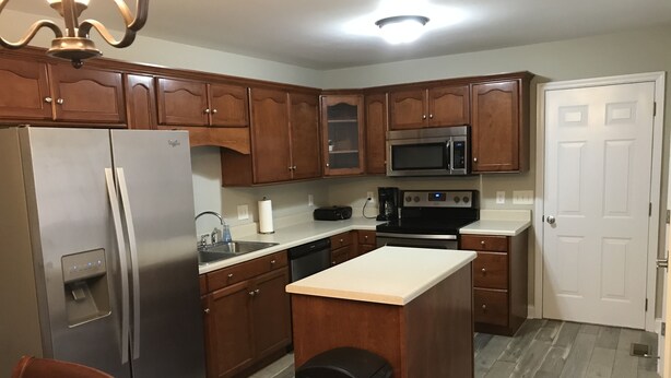 A kitchen with wooden cabinets, stainless steel appliances, a white countertop, and a built-in oven. - House near Lee University (Cleveland)