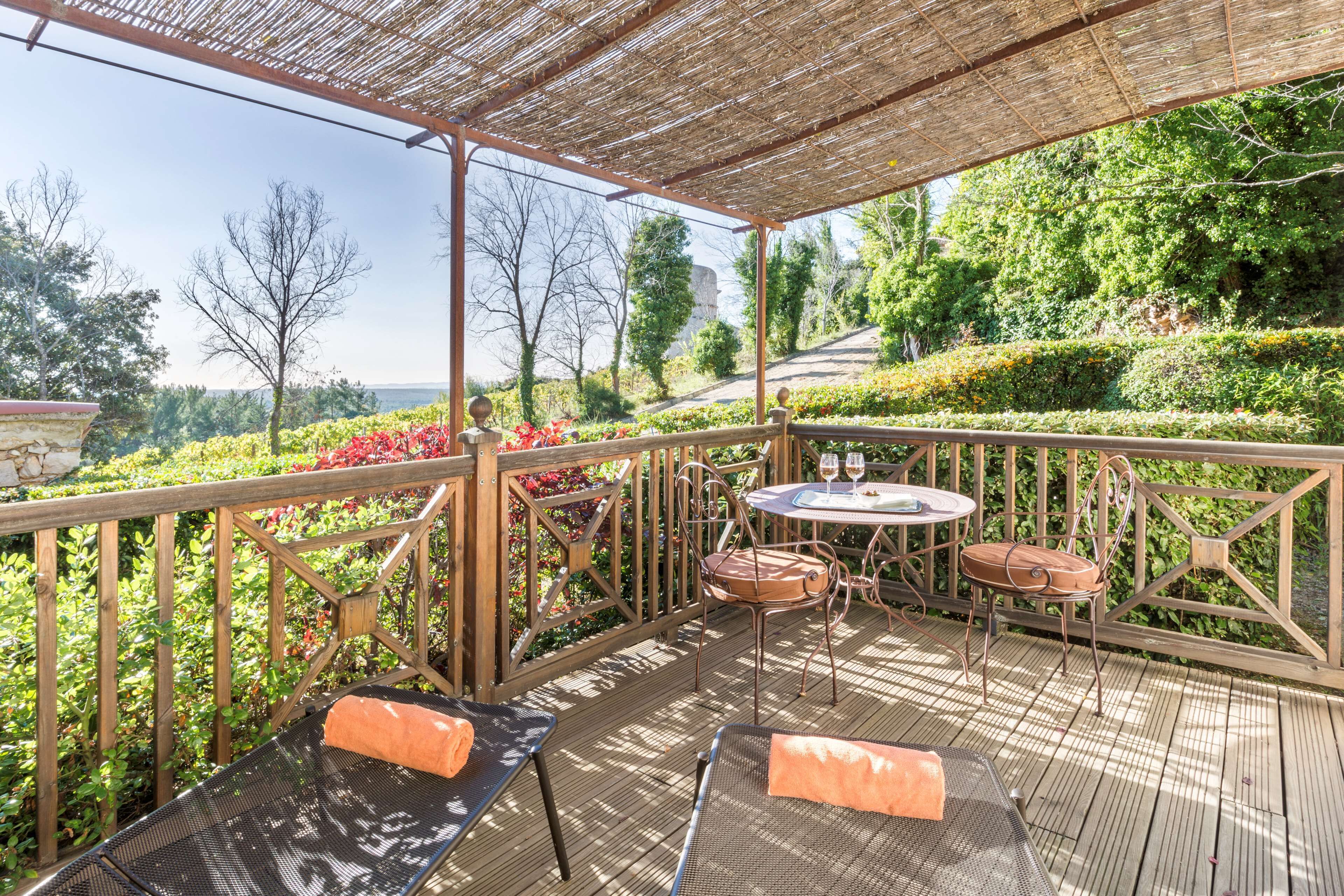 Eine Terrass mit Pergola, einer Sitzecke und Blick auf einen angelegten Garten.