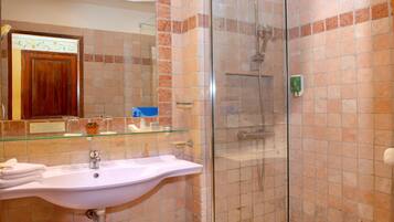 Un baño con ducha de vidrio, un lavamanos blanco y un espejo encima.