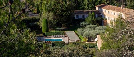 Una casa grande rodeada de árboles frondosos y una piscina.