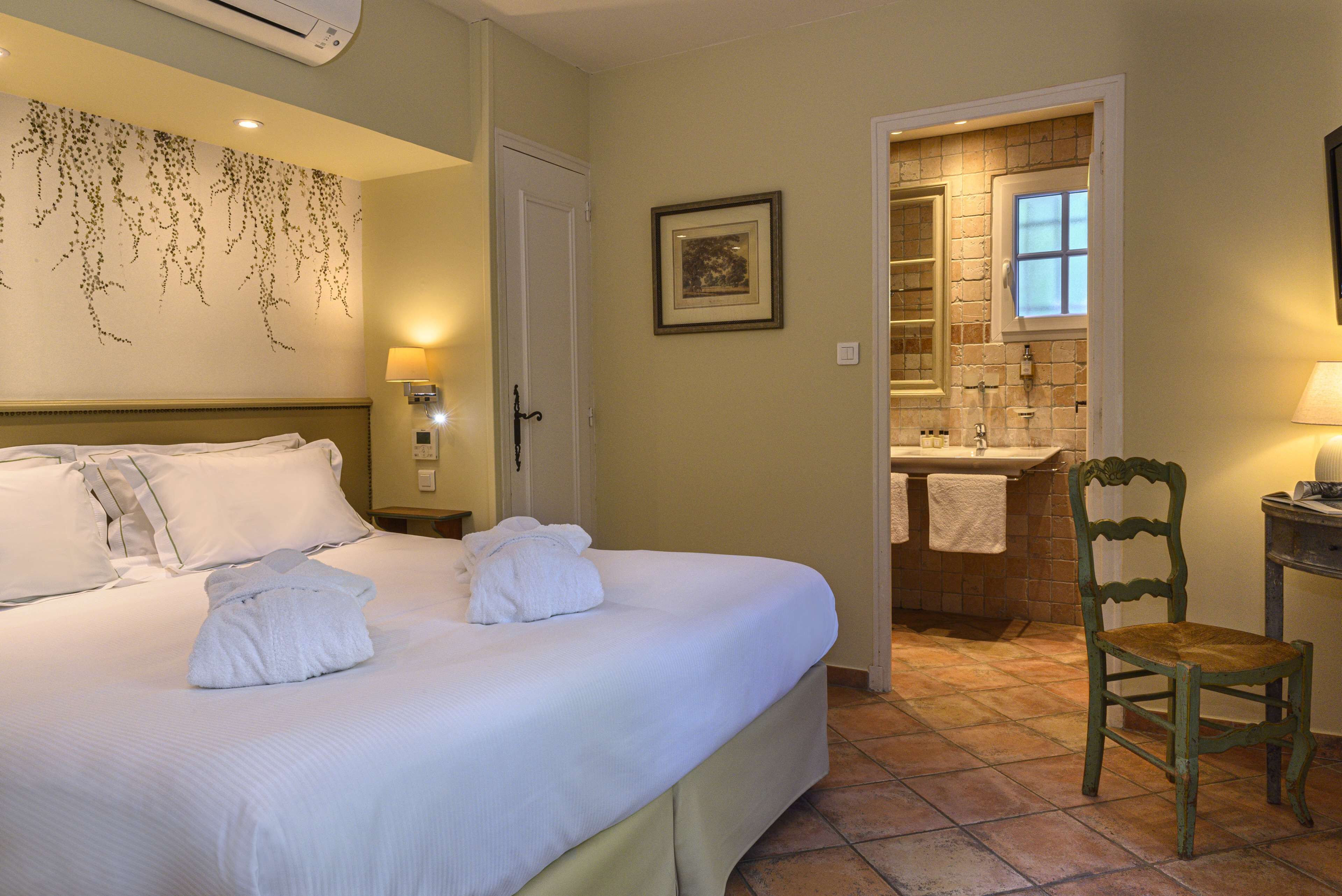 Una habitación de hotel con una cama grande, un baño con ventana y una silla.