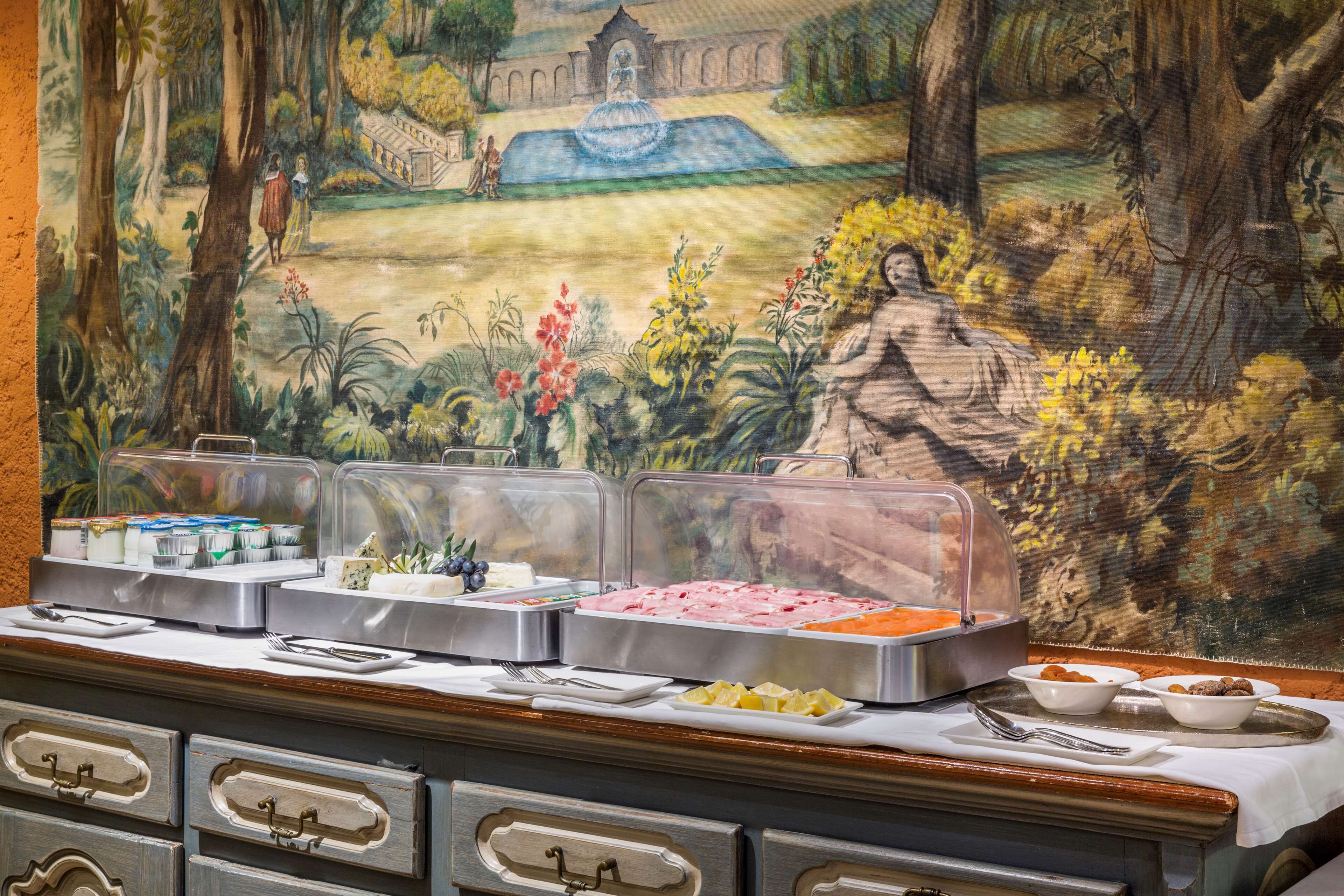A buffet setup with various food items and a decorative mural in the background.