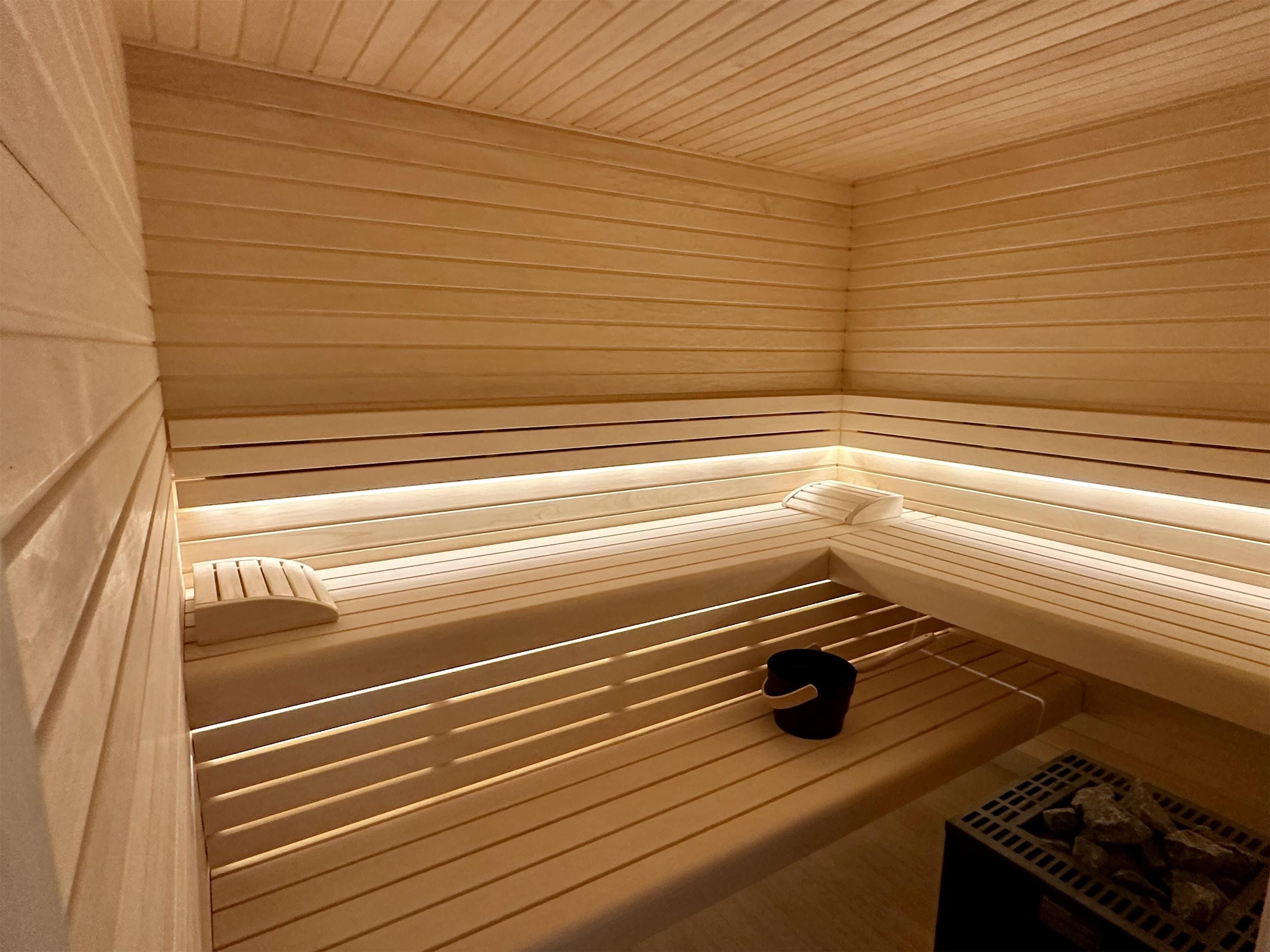 Una sauna con listelli di legno, una panca e un piccolo ripiano.