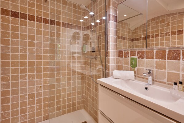 Un baño con ducha envuelta en vidrio, un lavabo blanco y un espejo.