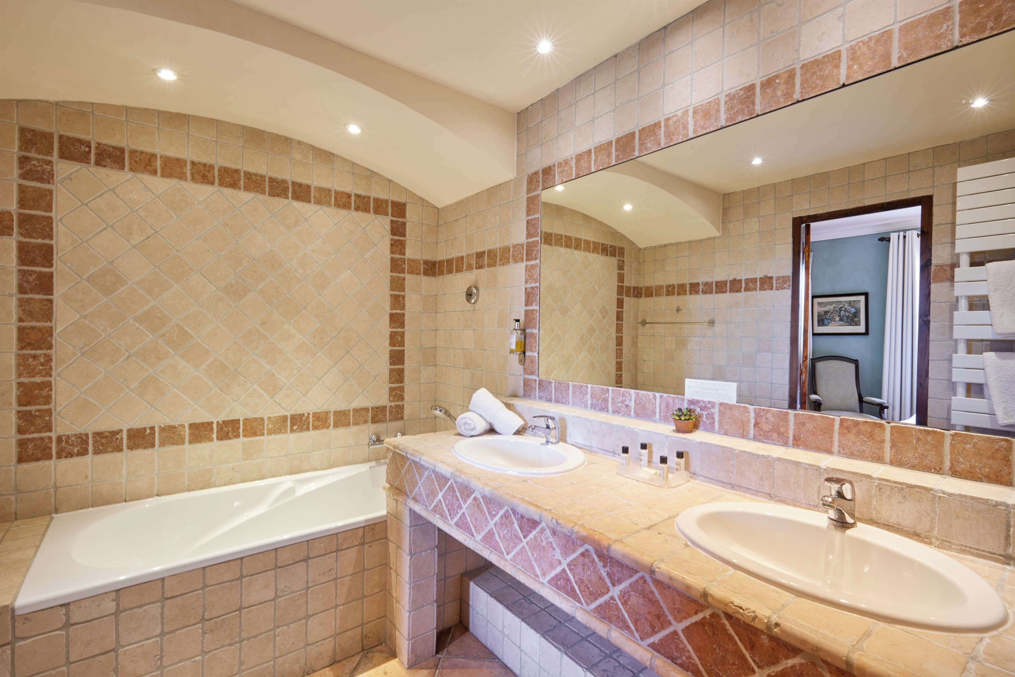 Een moderne badkamer met een bad, twee wastafels en een grote spiegel.
