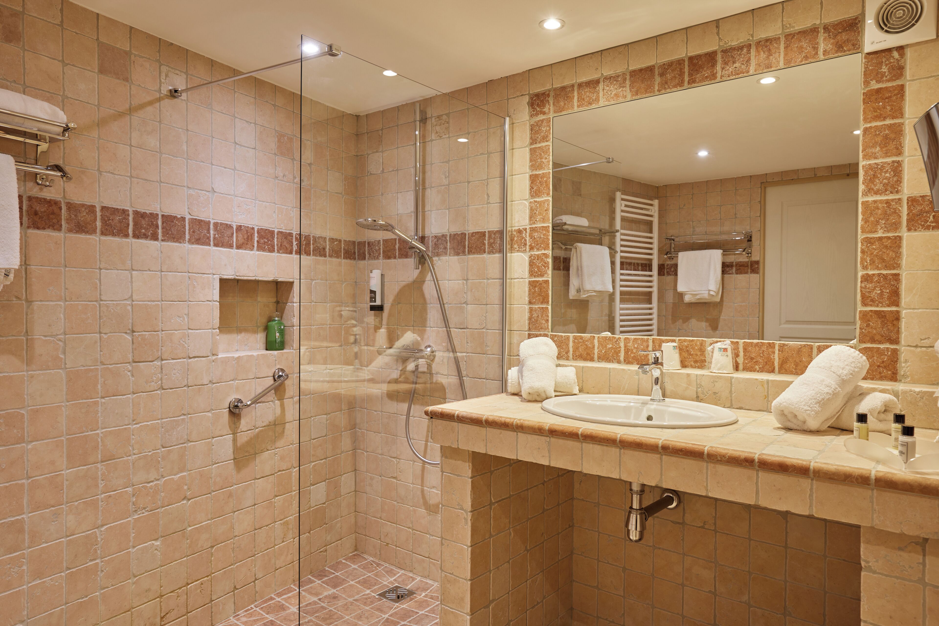A bathroom with a glass-enclosed shower, a sink, and a mirror.