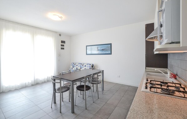 Una cucina compatta con un piano cottura a gas, un tavolo da pranzo con quattro sedie e un quadro incorniciato appeso al muro.