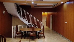 Un comedor con una mesa redonda y sillas, una escalera y paneles de madera.