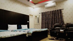 Un dormitorio con una cama grande, un sofá, una mesita pequeña y una cortina estampada.