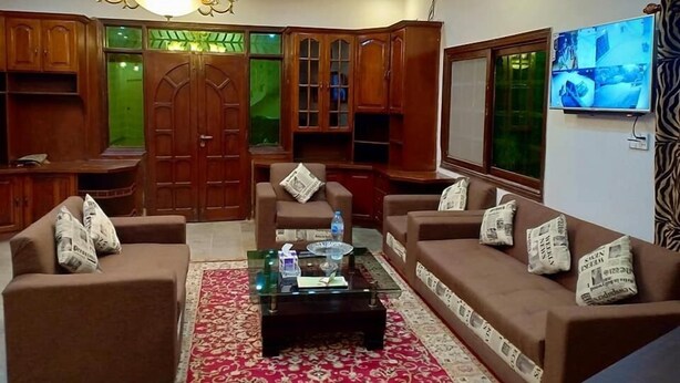 Una sala de estar con candelabro, sofás, una mesa de centro y una televisión.