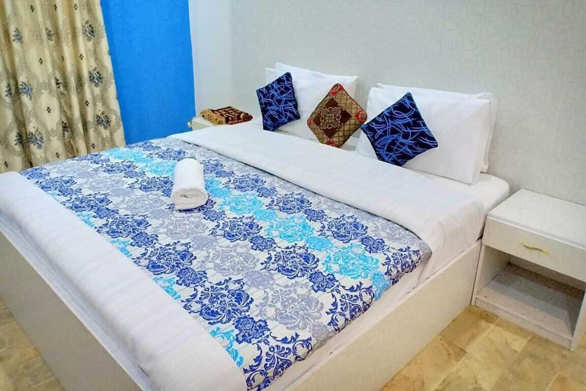 A hotel room with a bed, a nightstand, and a window with curtains.