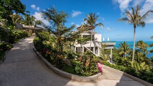 A modern building with a curved pathway leading to a balcony overlooking a coastal view. - Kapuhala (Koh Samui)