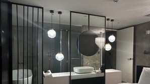 A modern hotel room with a large bed, a bathroom with a bathtub, and a mirror with three pendant lights. - Hotel Lesign (Yangsan)