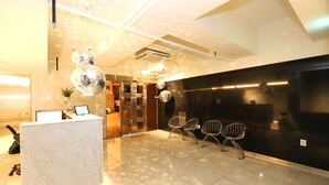 A modern lobby with a marble reception desk, a glass partition, and contemporary chairs. - Hotel Lesign (Yangsan)