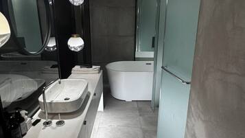 A modern bathroom with a double sink, a bathtub, and a large mirror.