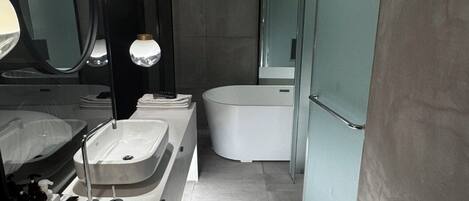 A modern bathroom with a double sink, a bathtub, and a large mirror.