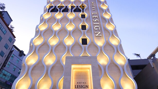 A hotel with a distinctive wavy facade and illuminated entrance. - Hotel Lesign (Yangsan)