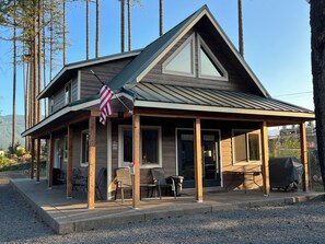 Un chalet à deux étages doté d’un porche couvert, d’une façade en bois et d’un drapeau américain.