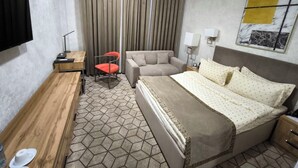 Een hotelkamer met een bed, een bureau, een stoel, een bank en een televisie.