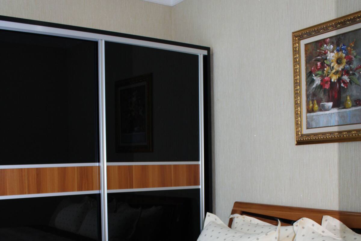 A hotel room with a large bed, a wooden headboard, a painting on the wall, and a sliding door.