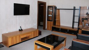 Een moderne woonkamer met een flatscreen televisie, een houten tv-meubel en een salontafel.