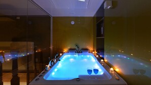 A modern spa room with a large, illuminated hot tub, two glasses of blue liquid, and candles. - Camel Pension (Gapyeong)