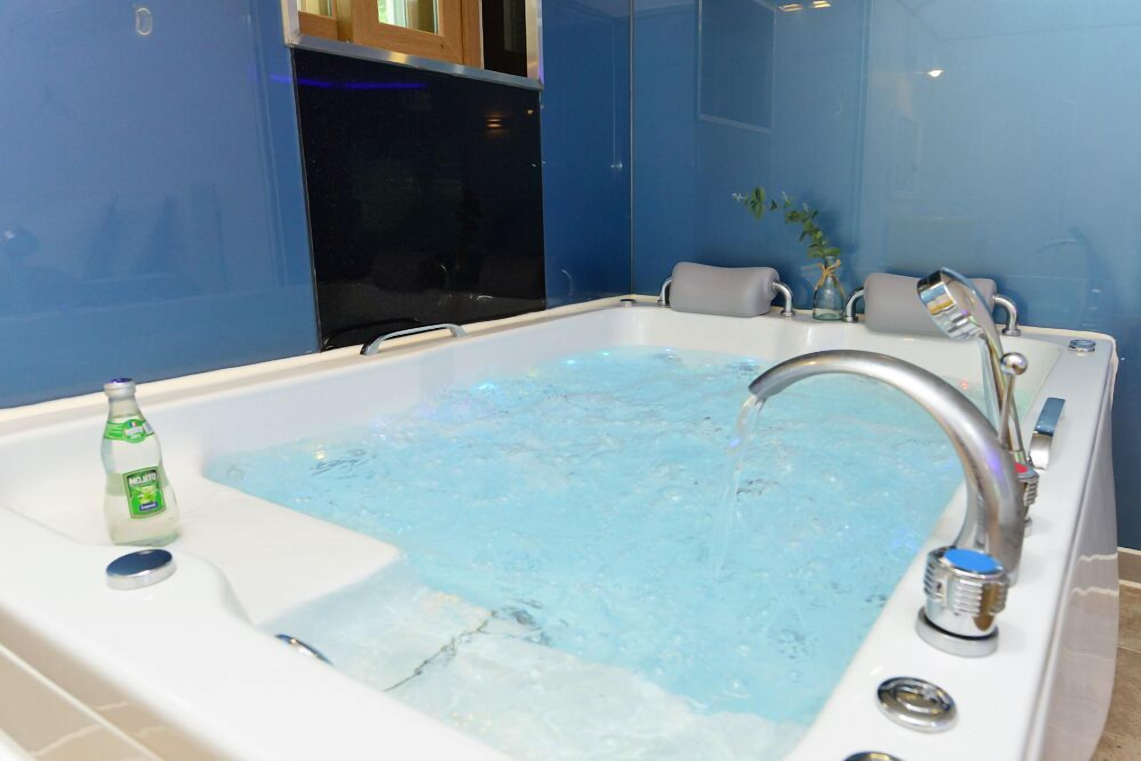 A modern bathroom with a bathtub, a bottle of mouthwash, and a plant.