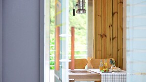 A dining area with a wooden table and chairs, a checkered tablecloth, and a bottle of juice. - Camel Pension (Gapyeong)