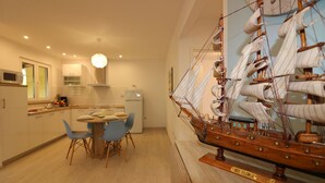 A modern kitchen with a dining area, a ship model, and a wooden plaque reading "May Flower."