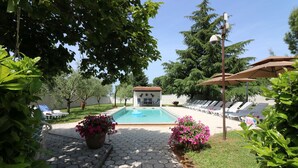 A swimming pool with lounge chairs and a small building in the center.