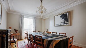 A dining room with a large table, chairs, a chandelier, and a painting on the wall. - Suburban Peace in Neuilly-Sur-Seine, by Veeve (Paris)