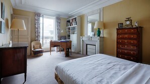 A bedroom with a bed, a desk, a chair, a bookshelf, a dresser, and a fireplace. - Suburban Peace in Neuilly-Sur-Seine, by Veeve (Paris)