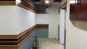 A narrow hallway with a potted plant, wooden trim, and a door with a white frame. - Richmart Resthouse (Barisal)